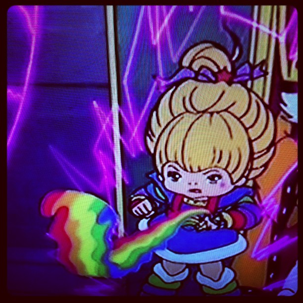 a cartoon figure holding a rainbow ball near a neon background