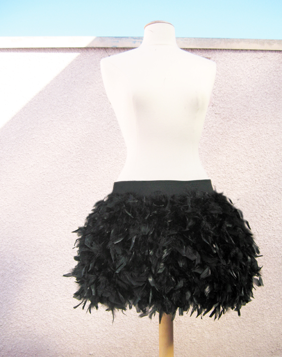 a dress form with a black feather skirt