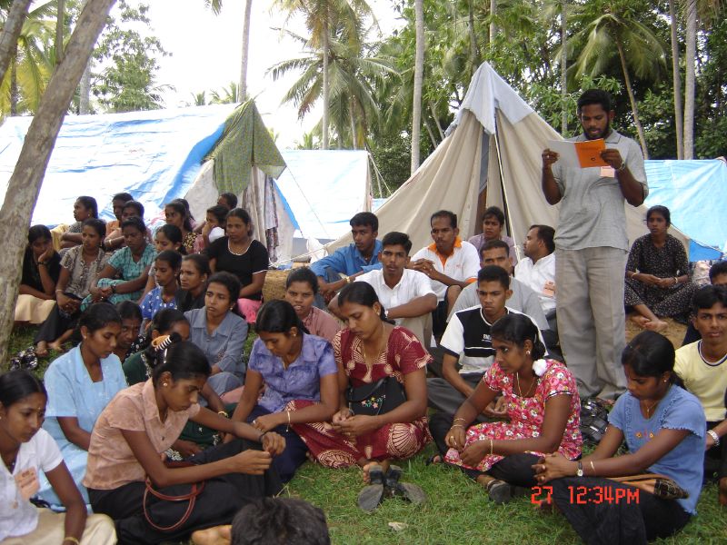 many people sitting in the grass with tents