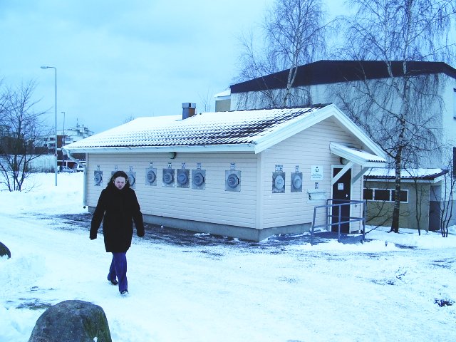 a woman walking through snow next to a building