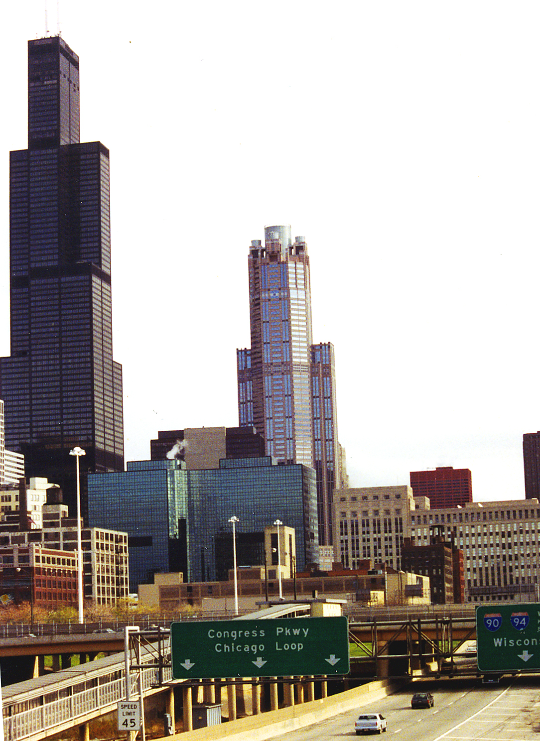 a freeway with traffic traveling down it, next to tall buildings