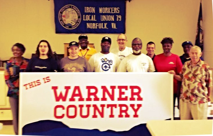 a group of people stand behind a large sign that says, this is warner country