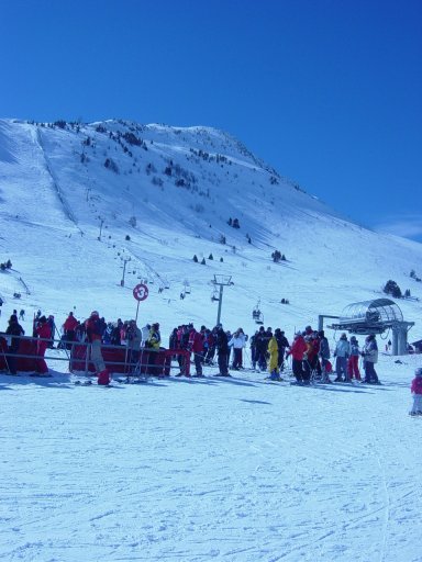 a crowd of skiers waiting in line for a lift
