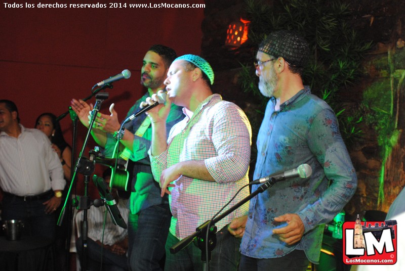 three men on stage at an event with a microphone