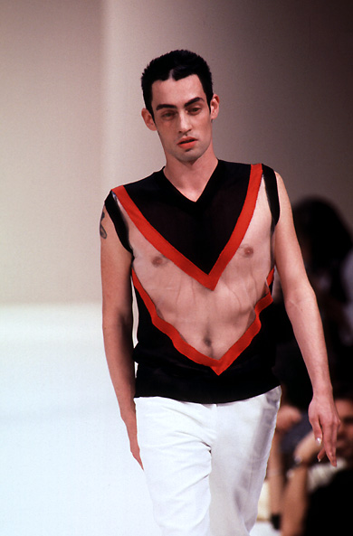 a man wearing white pants on the catwalk