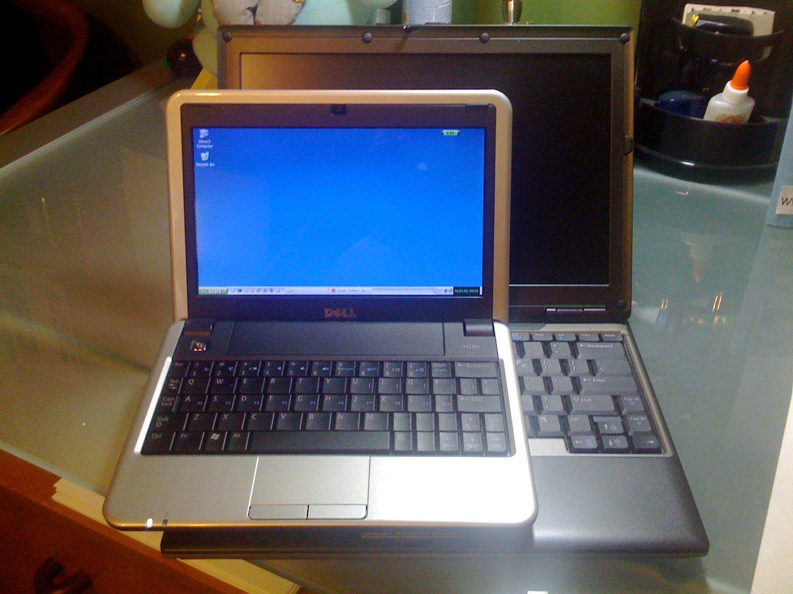 two laptop computers sit on a glass table