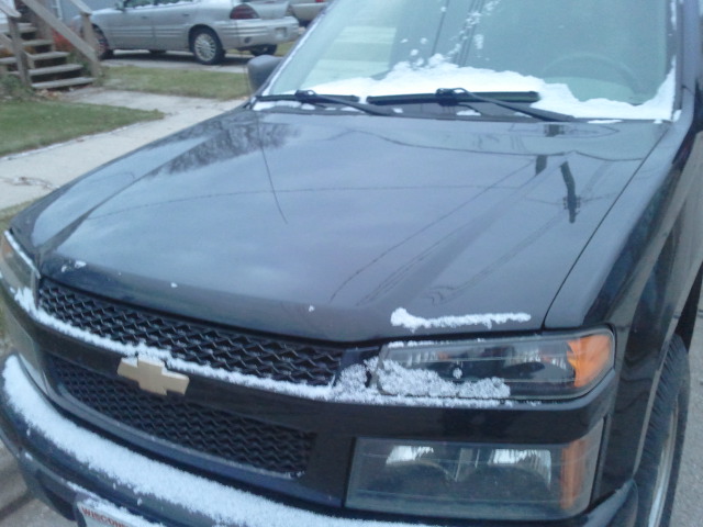 a truck with snow on the hood and front lights