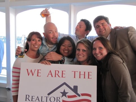several people pose with a realtor sign