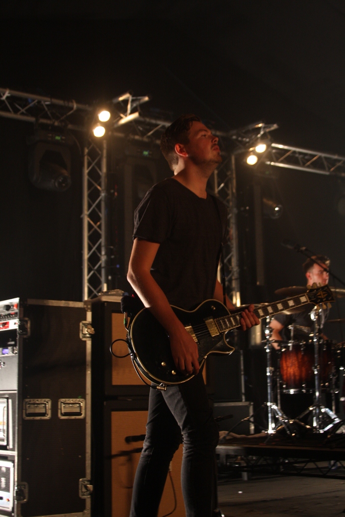 a man holding a guitar on stage with lights in the background