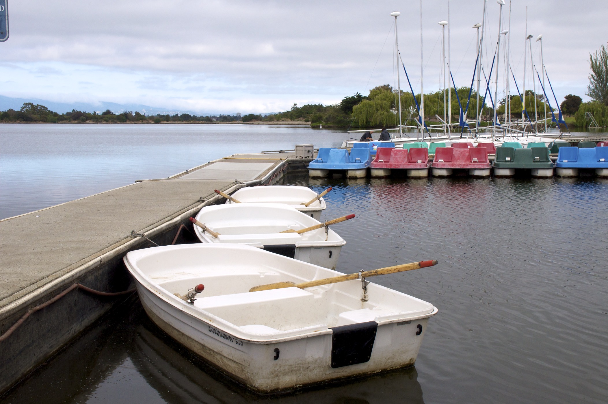 a row of four boats sitting in the water by the dock