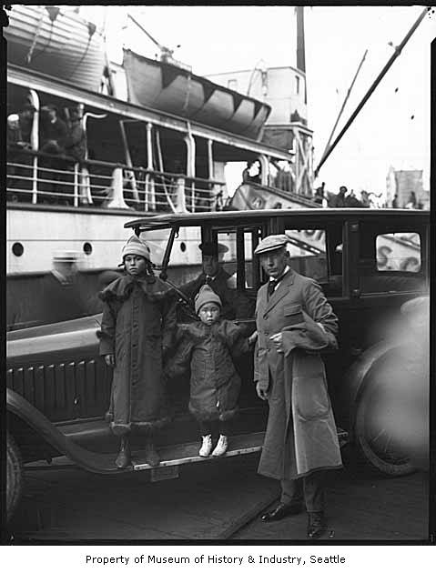 black and white pograph of family with antique bus