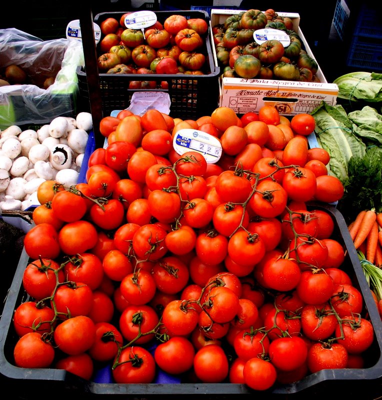 fresh vegetables on display in trays at an outdoor market