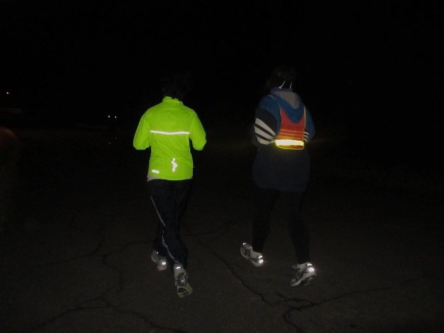 two people on skateboards are lit up in the dark