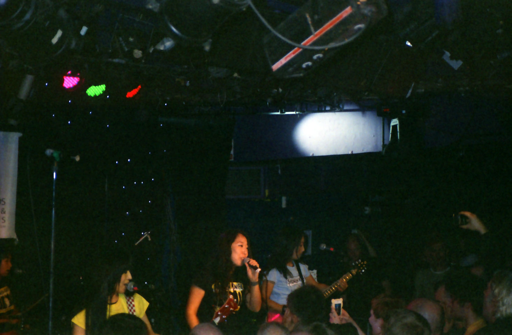 a person on a stage that has people and one has a guitar