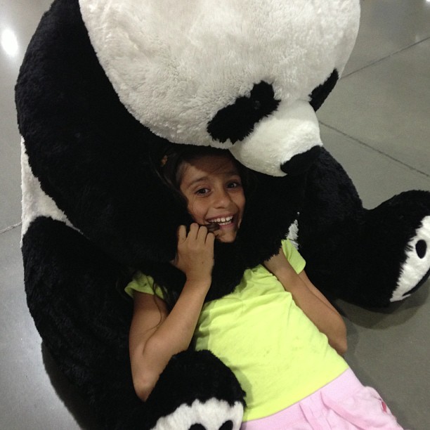 a girl holding a giant stuffed panda bear in her arms