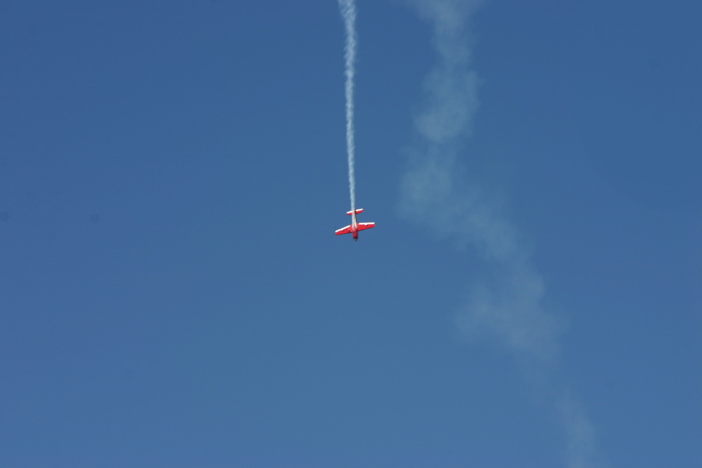 an airplane flying upside down under a blue sky
