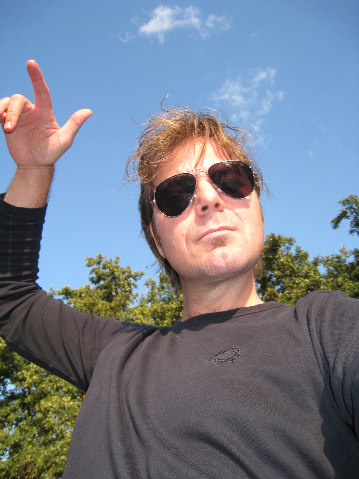a man wearing sunglasses and a black shirt posing with the peace sign