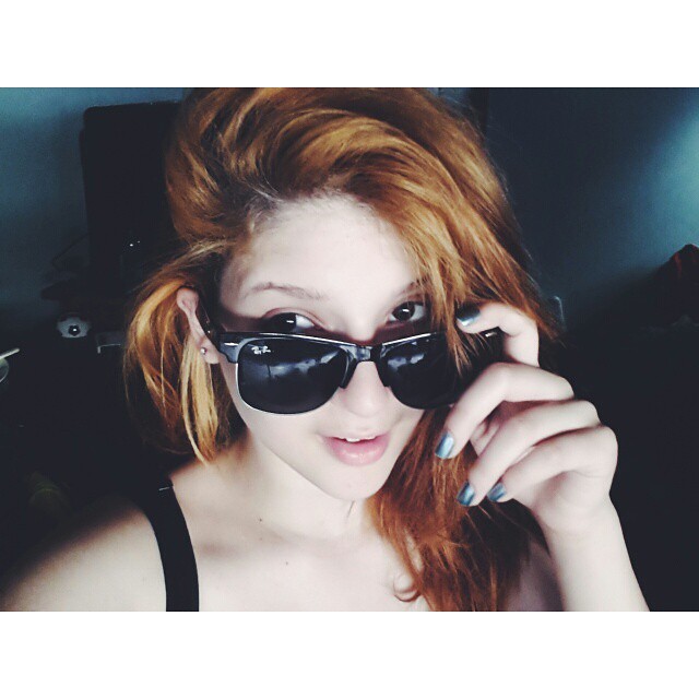 a young woman with red hair wearing black sunglasses