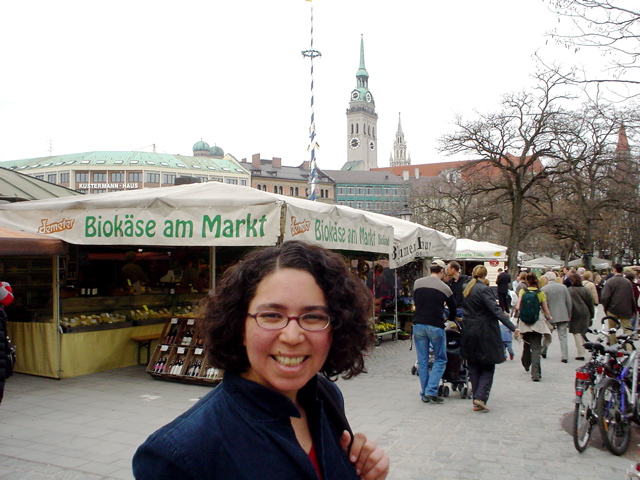 a woman smiling while standing in front of a market