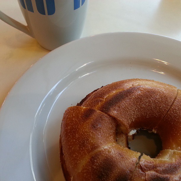 a white plate with donut on it and a coffee cup