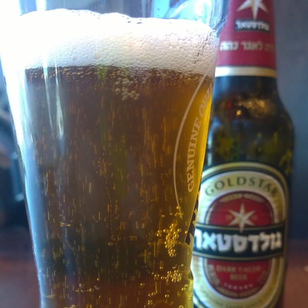 a glass with beer sitting next to a bottle