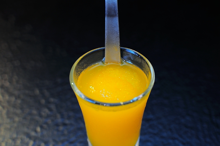 glass filled with orange juice and a spoon sticking out of the top