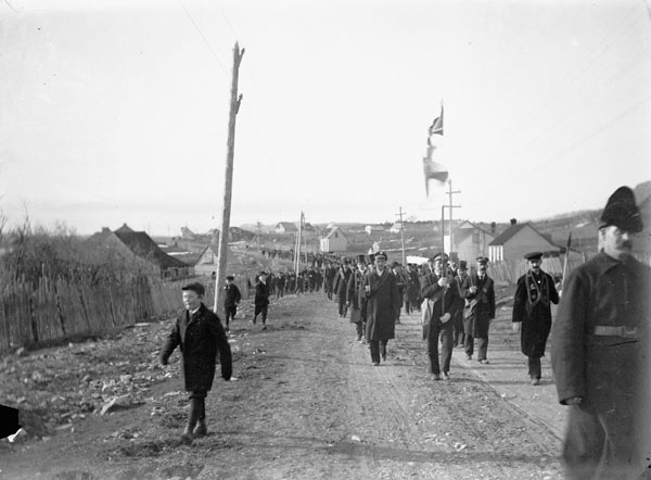 soldiers marching down a city street near a fence