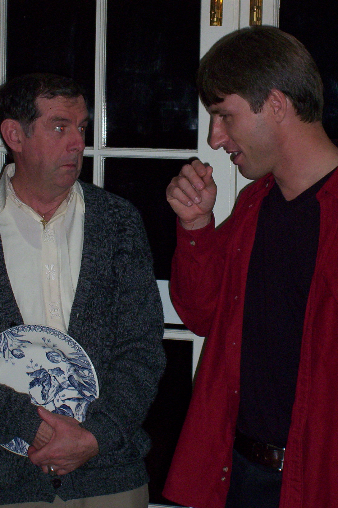 a man in red and black jacket talking to another man