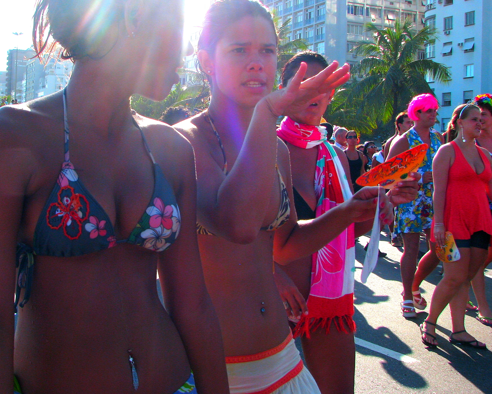 two s in bikinis stand near a crowd