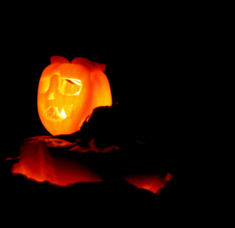a pumpkin lantern sits on a black surface with the light glowing