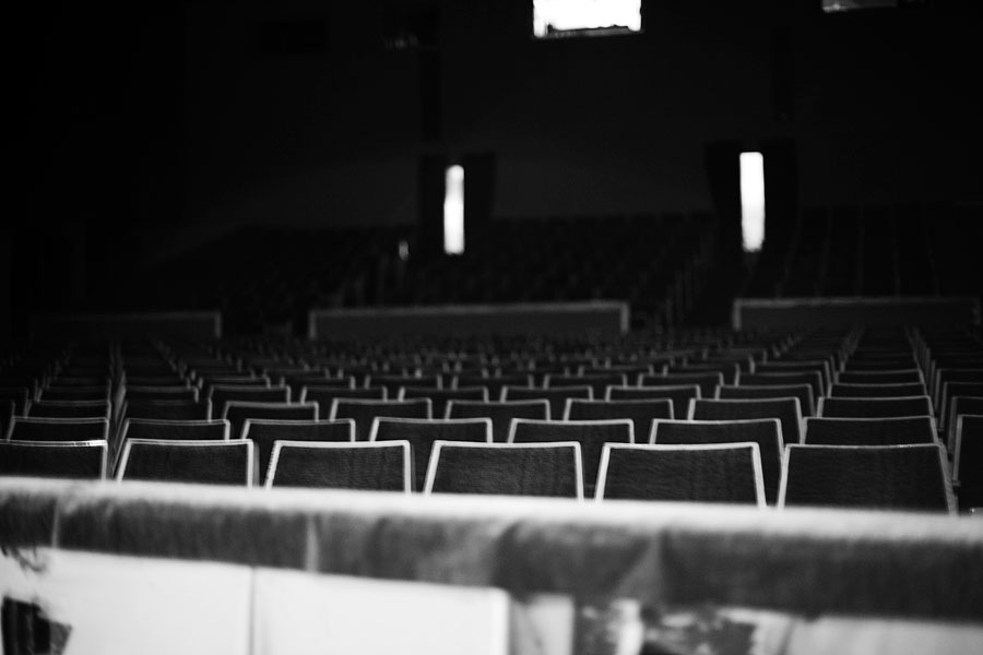 empty auditorium seats in black and white, one light shining on the seats