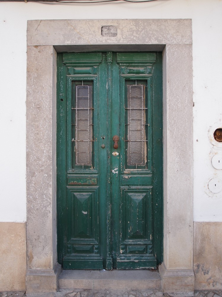 two green doors on an old stone building