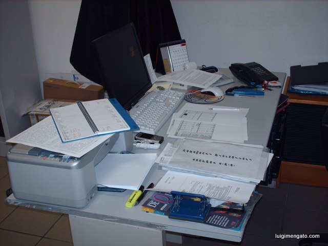 a desk covered with various computer equipment and paperwork