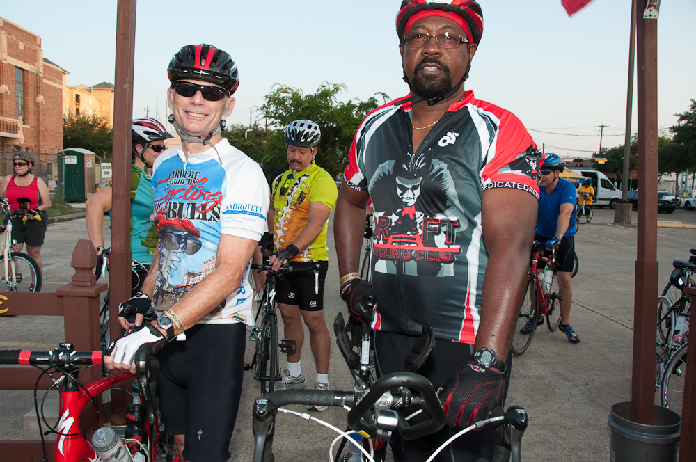 two people in bicycles wear gear and standing in front of them