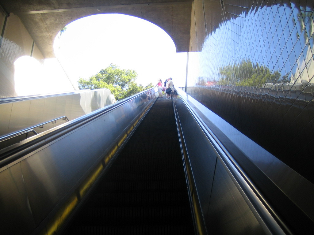 an escalator with some people going down it