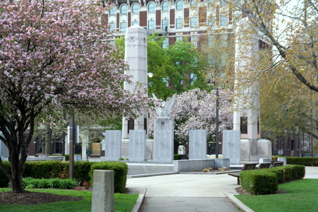 an empty cemetery surrounded by trees, with benches and plants on either side