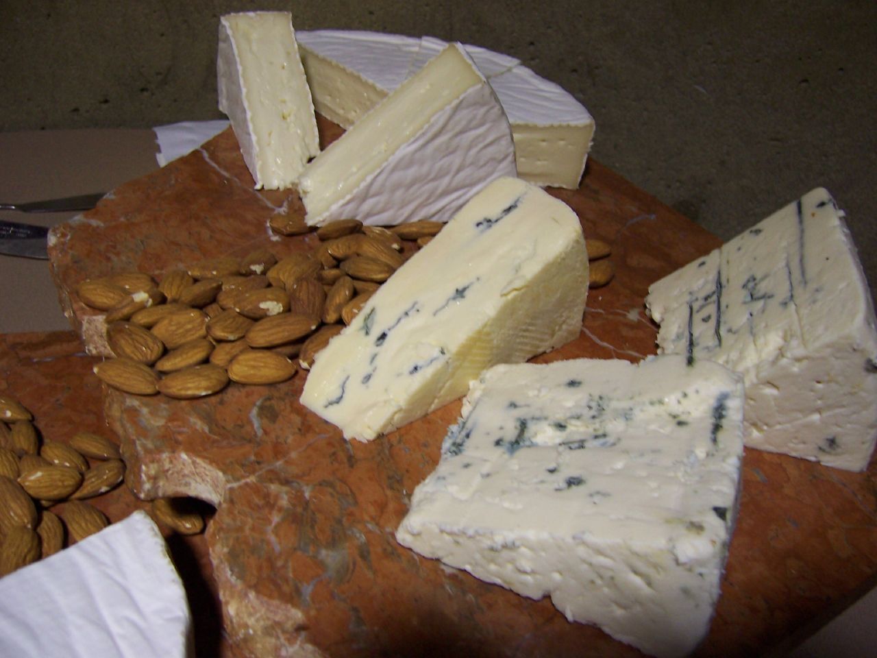 four different cheeses, including almonds, on a table