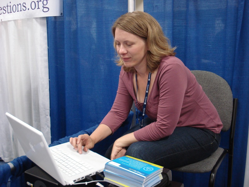 the woman is using a white laptop and has a folder