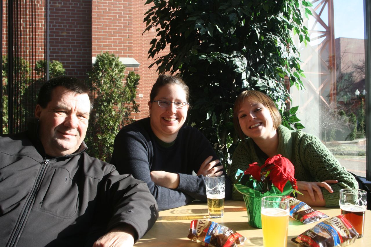 three people sit at a table in front of the window