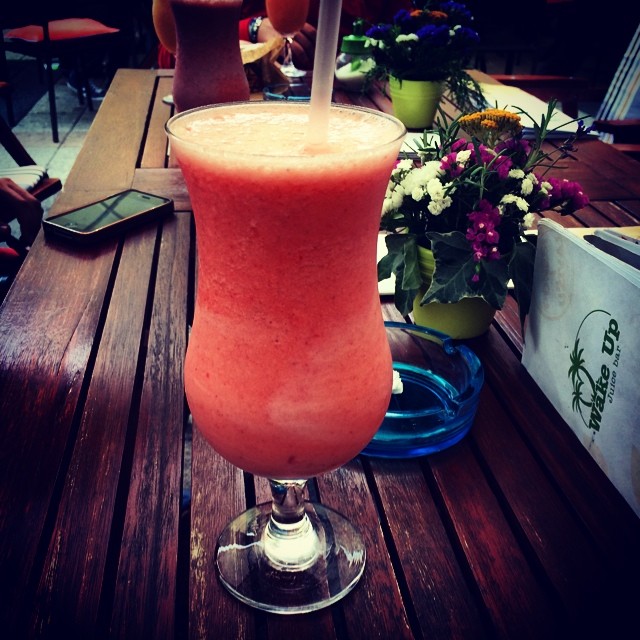 a pink drink sitting on a wooden table