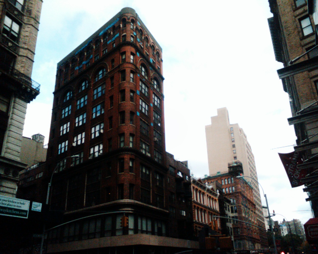 some tall buildings and people walking on a sidewalk