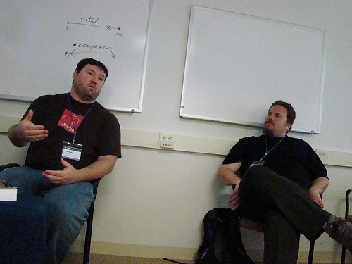 two men talking while sitting down in a conference room