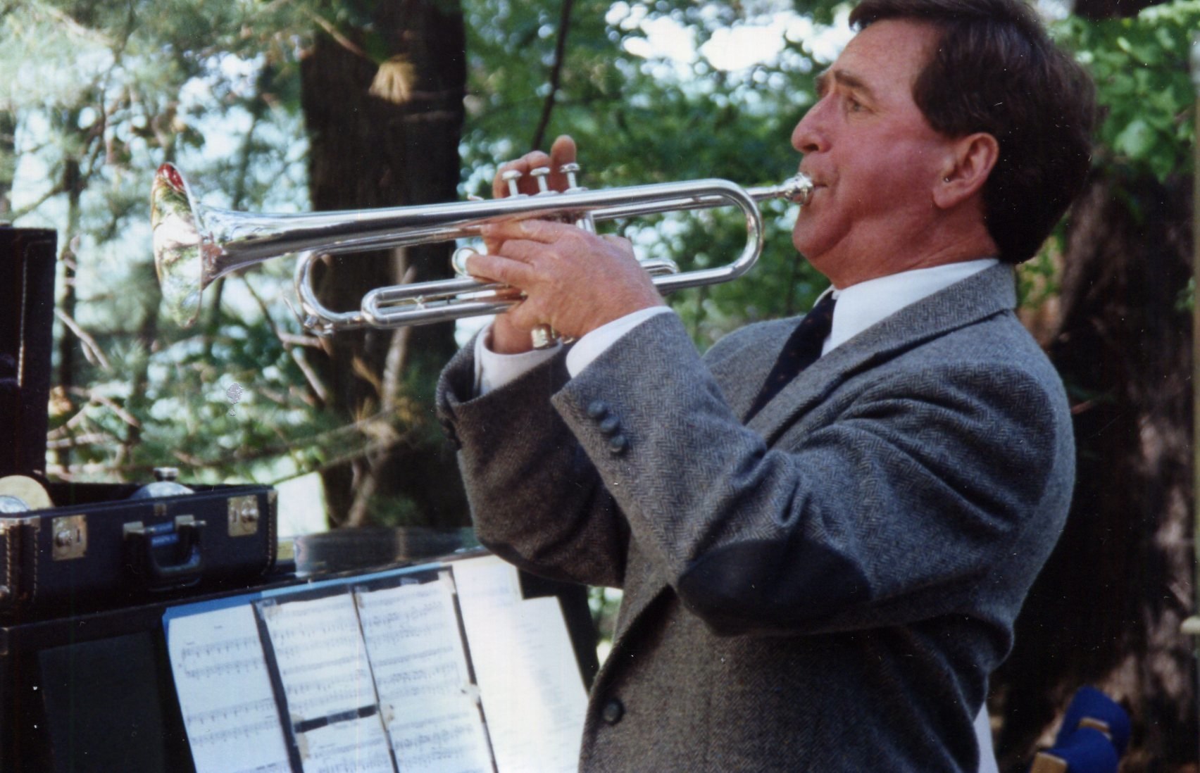 a man in a gray suit is playing a trumpet