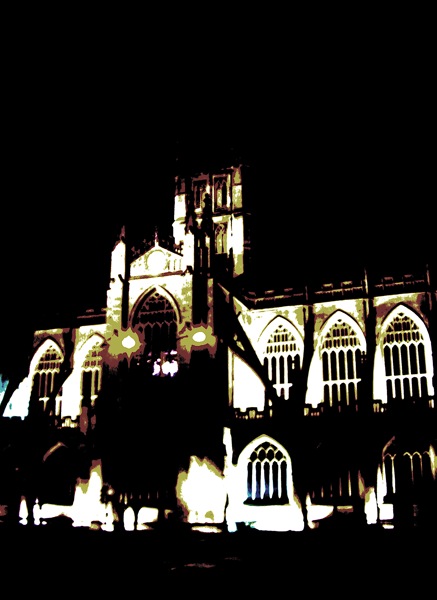 a lighted cathedral with a clock tower in the dark