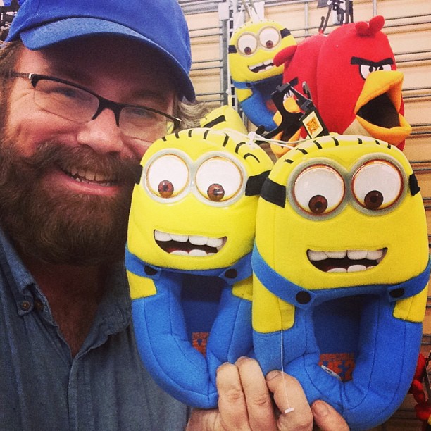 a man smiling while holding up some toy minions