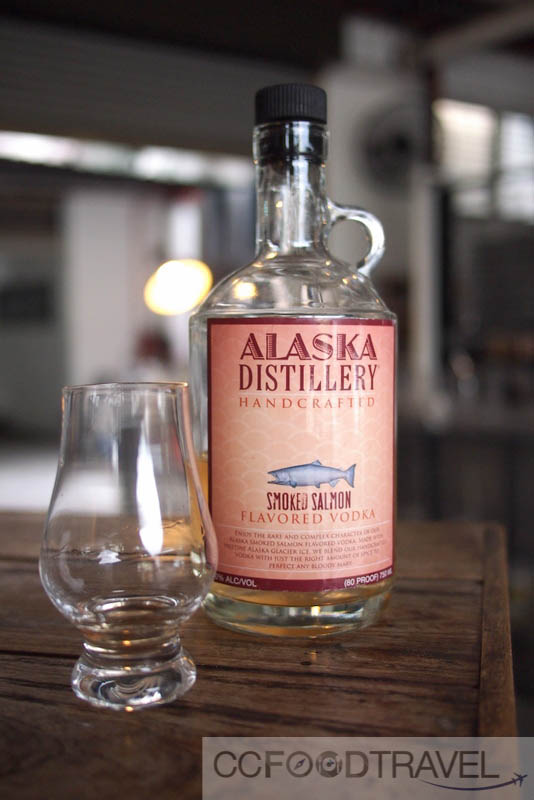 a bottle of alaska distillery, next to a wine glass