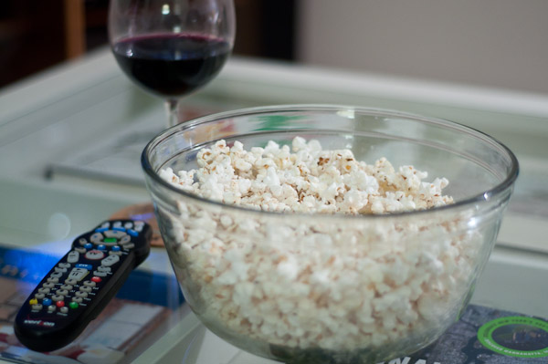 bowl filled with popcorn and a drink next to it
