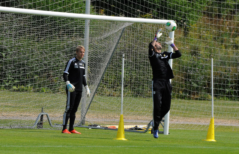 two men stand in front of a soccer net