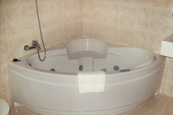 a large bathtub sits in the middle of a beige tiled bathroom