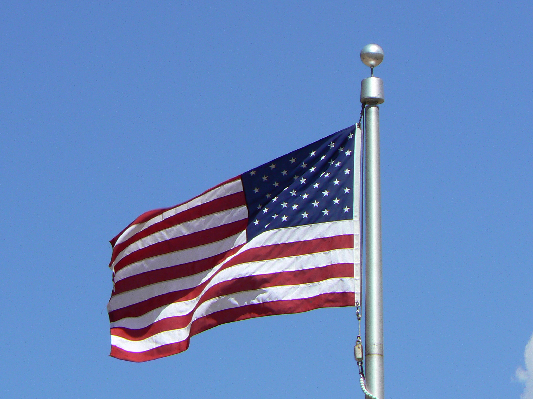 an american flag on the pole with a clear blue sky in the background